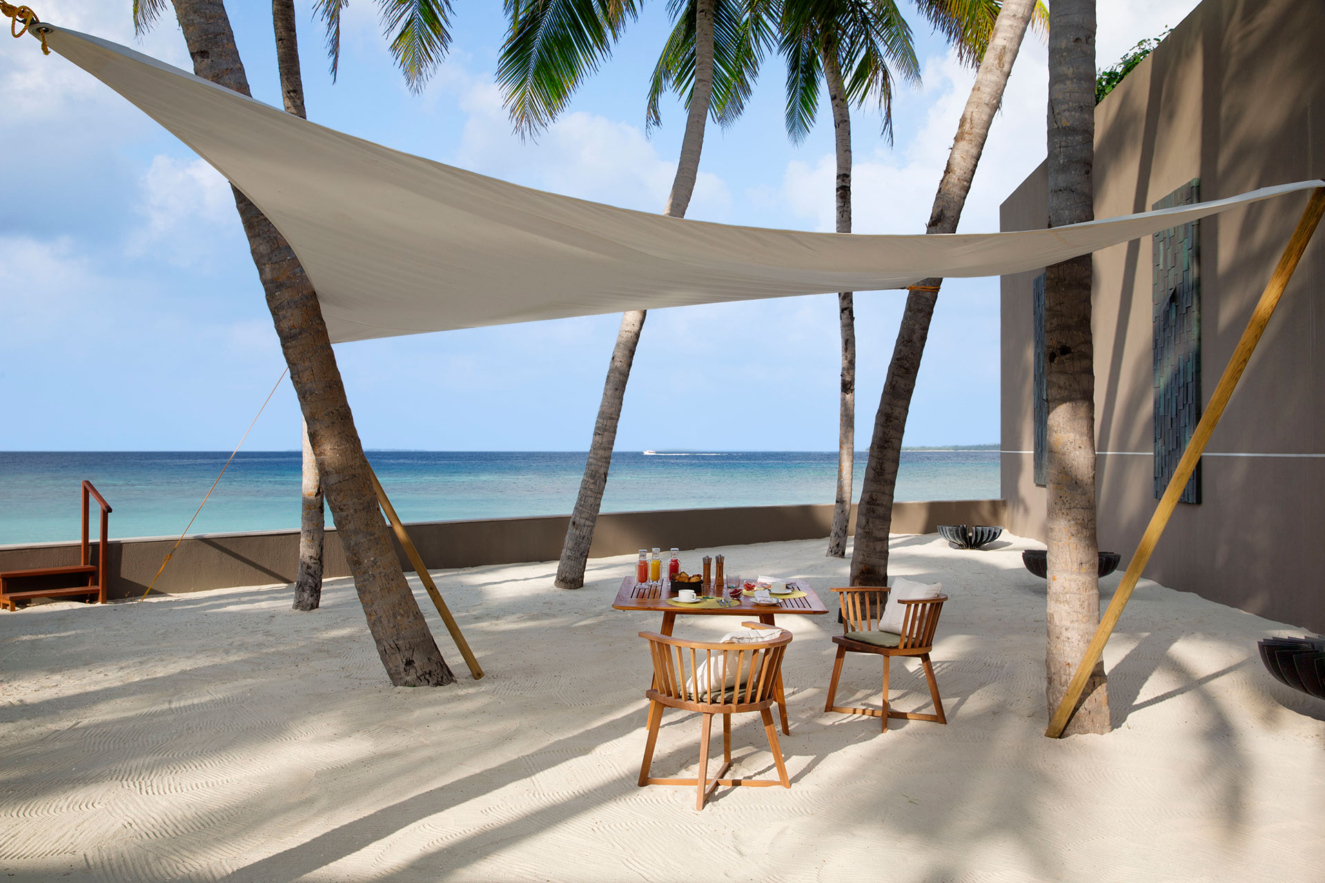 Esstisch im Sand unter Sonnensegel