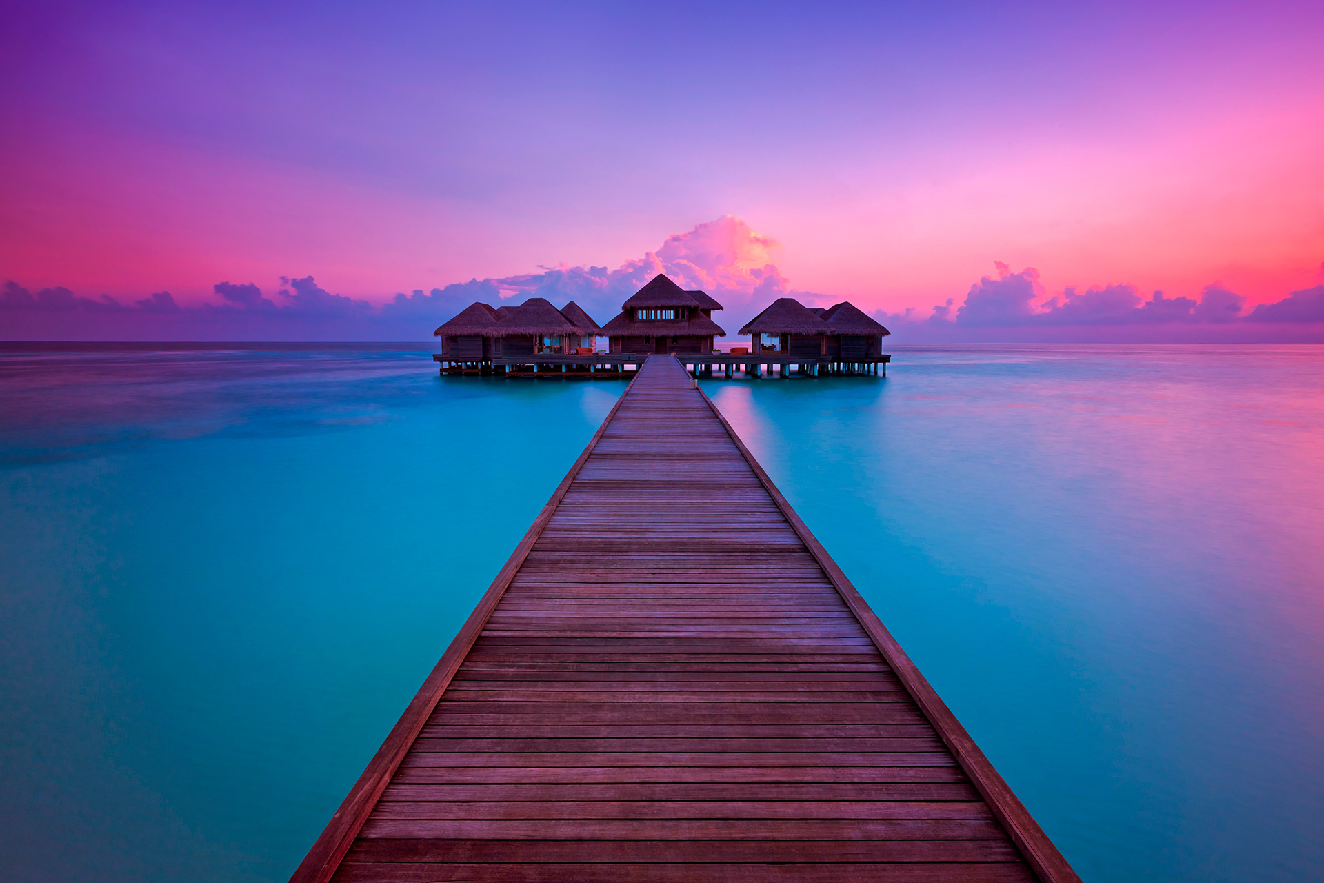 Holzsteg mit Wasservillen im Abendrot
