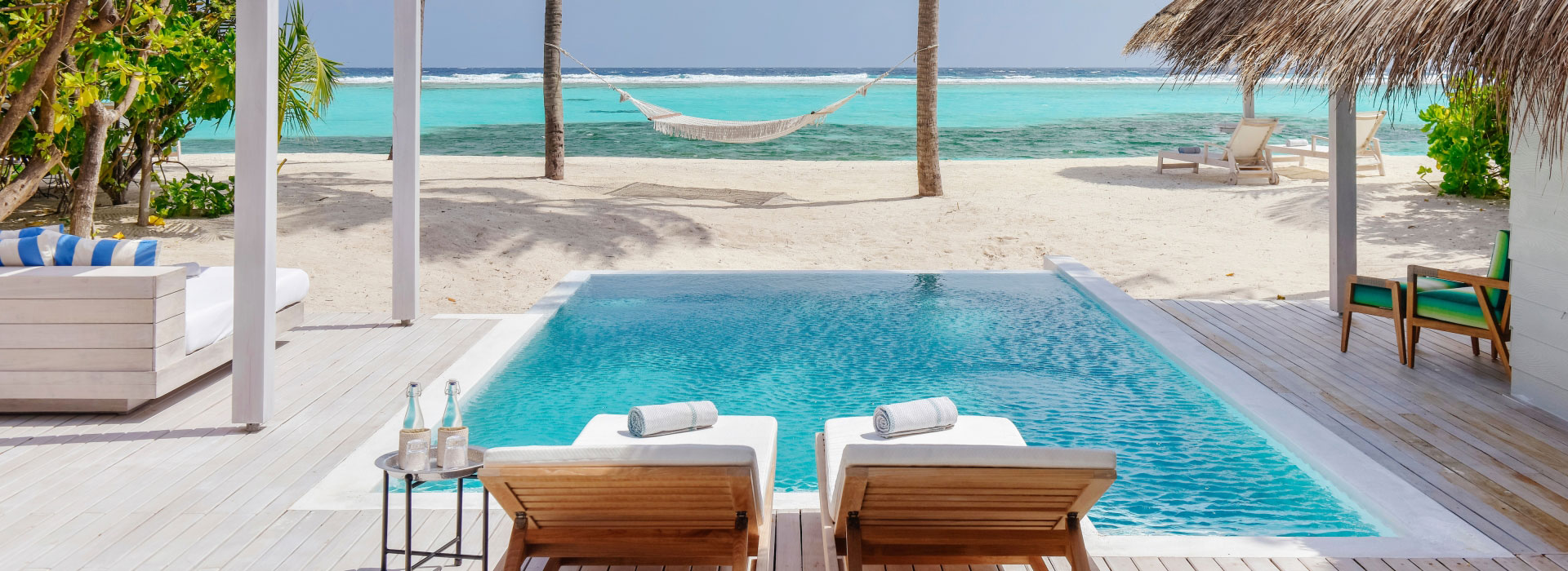 Liegen vor einem Pool mit Strandblick